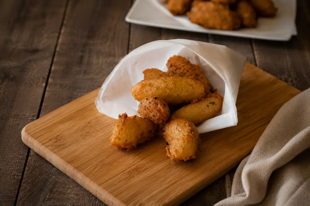 Golden Sicilian potato croquettes served hot in a paper cone.
