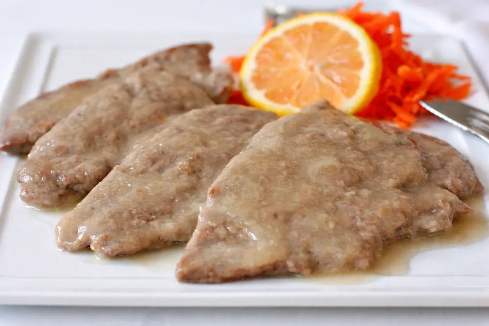 Close-up of Scaloppine al Limone with lemon slice and sauce.