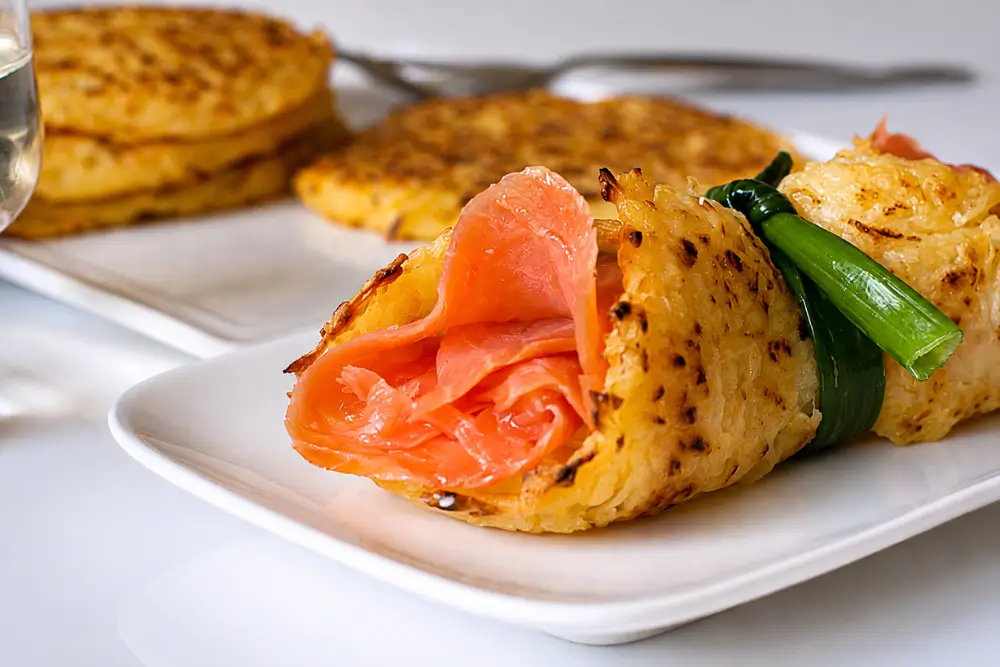 Thin rösti rolled with smoked salmon and tied with a spring onion stem.