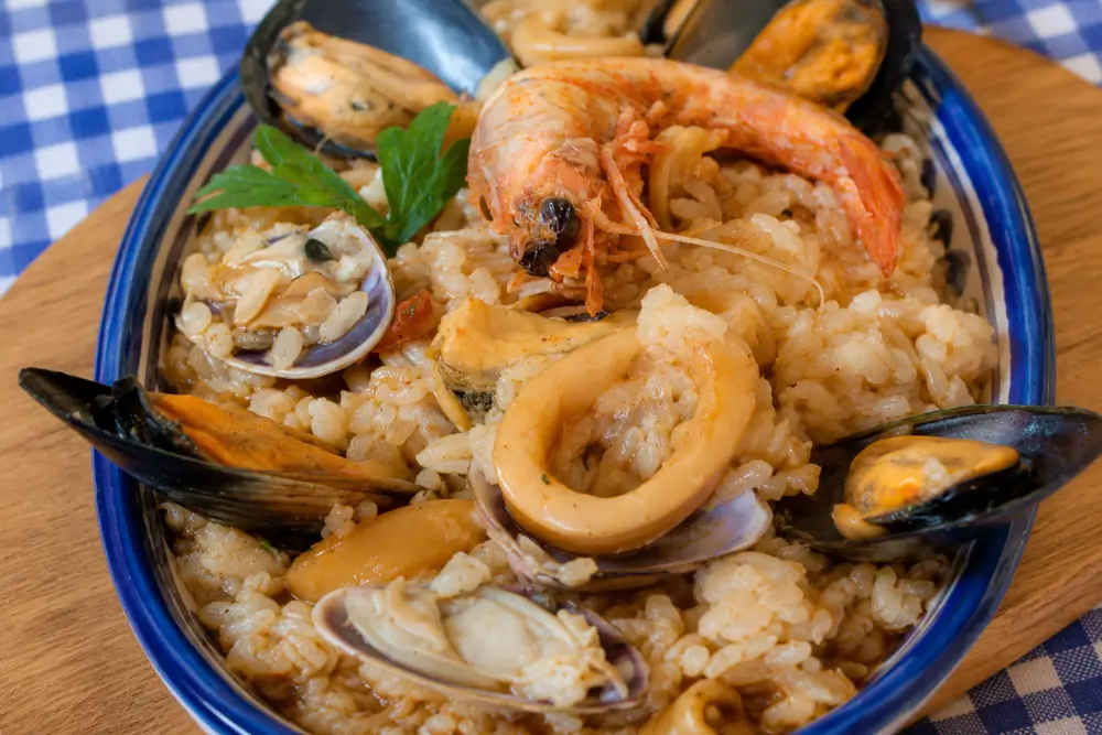 Close-up of Italian seafood risotto on a serving plate with shellfish and calamari.