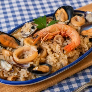 Risotto alla Marinara served on a plate with prawns, mussels, clams, and calamari.