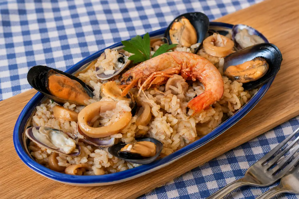 Risotto alla Marinara served on a plate with prawns, mussels, clams, and calamari.