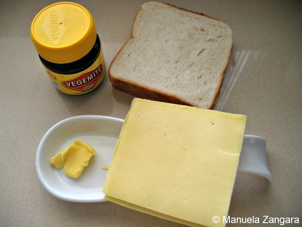 IMG_5823 Ingredients for Vegemite sandwich including white bread, butter, cheese, and a jar of Vegemite.