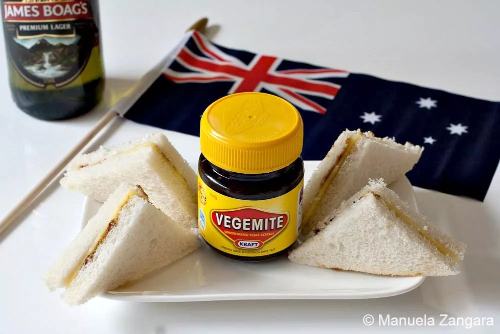 Mini Vegemite and Cheese Sandwiches Vegemite and cheese sandwiches served with an Australian flag and a bottle of beer in the background.