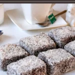 Lamingtons coated in chocolate icing and coconut arranged neatly on a serving plate.