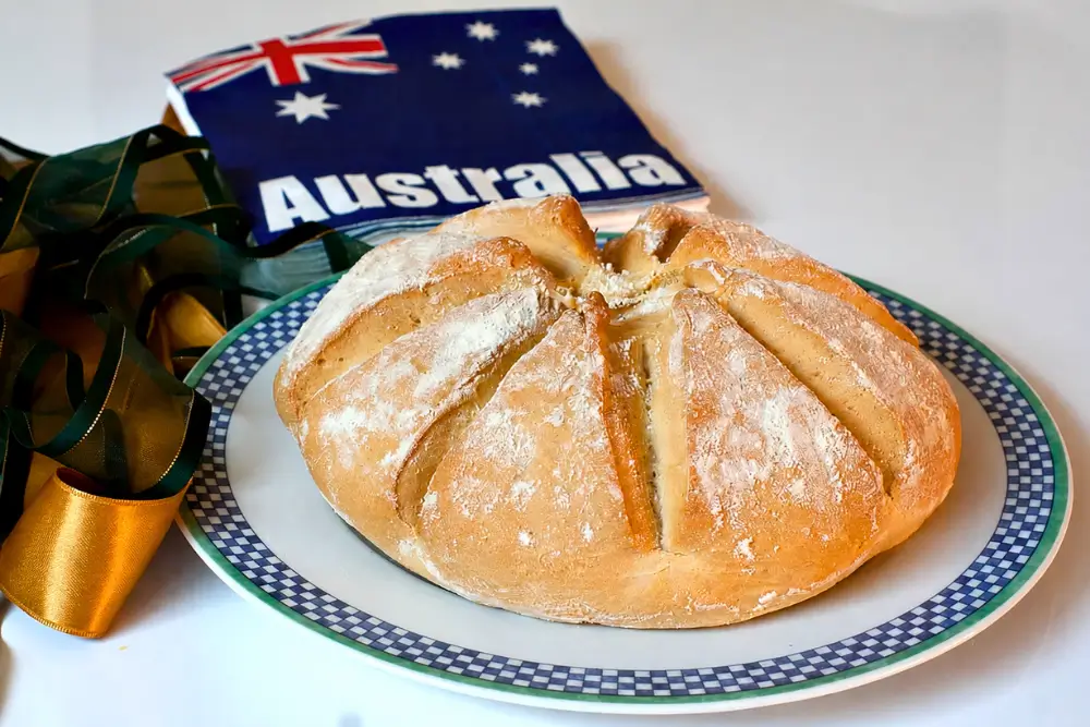 Freshly baked Australian damper dusted with flour and served on a plate.
