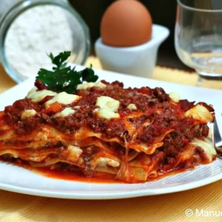 Slice of baked lasagne on a white plate.