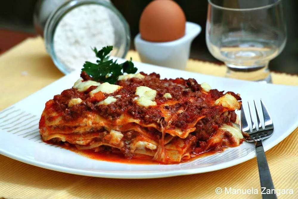 Lasagne Slice of baked lasagne on a white plate.