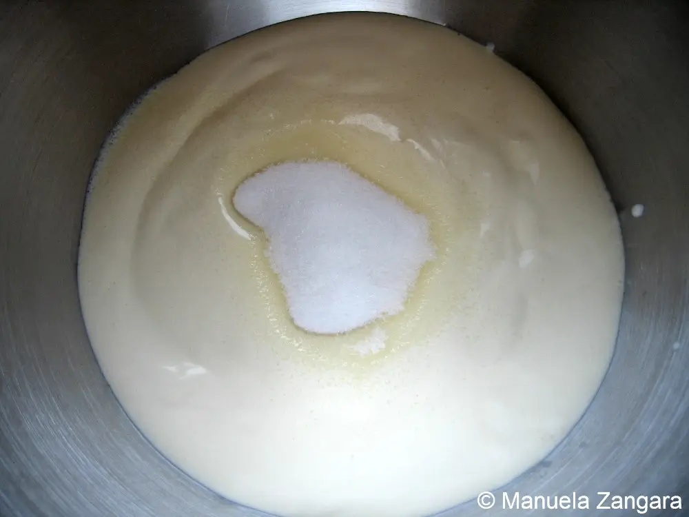 Caster sugar added to egg whites in mixing bowl.