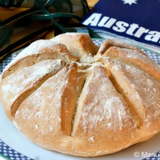 Close-up of the baked Damper loaf with visible scoring and dusted flour.