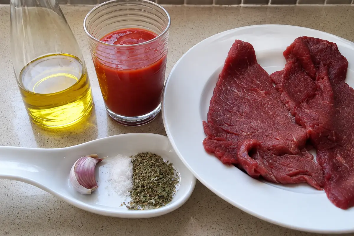 Beef schnitzel with tomato purée, olive oil, garlic, oregano and salt.