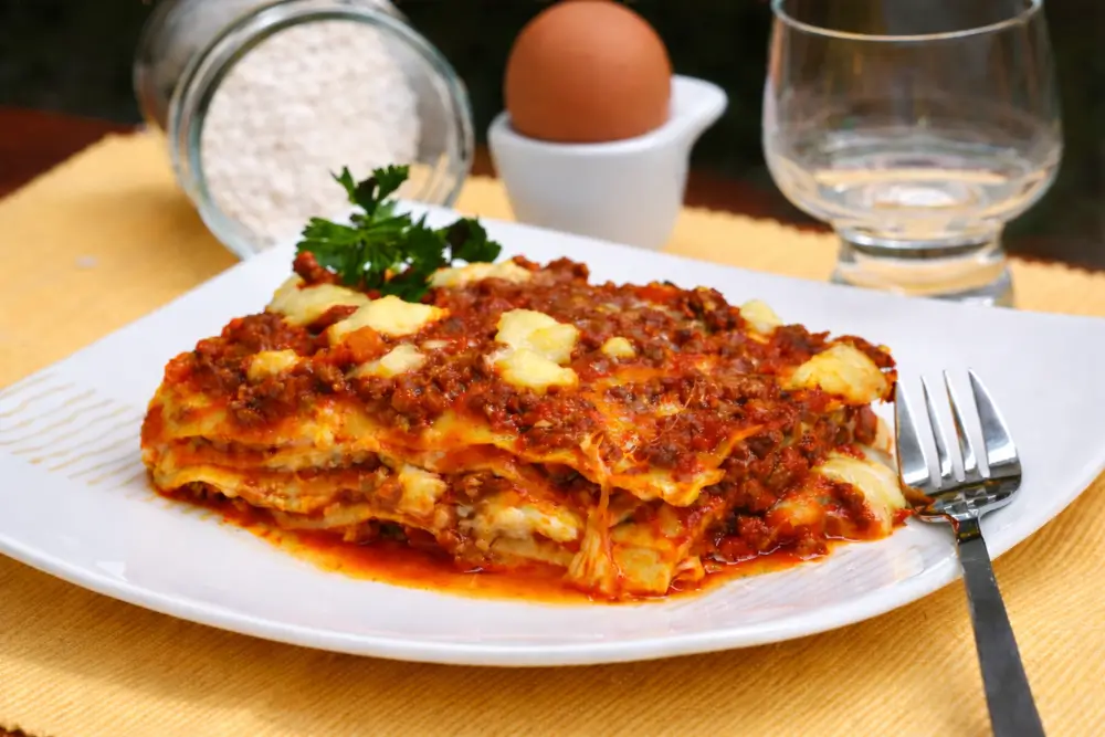 Lasagna portion served on a plate with sauce and melted cheese.