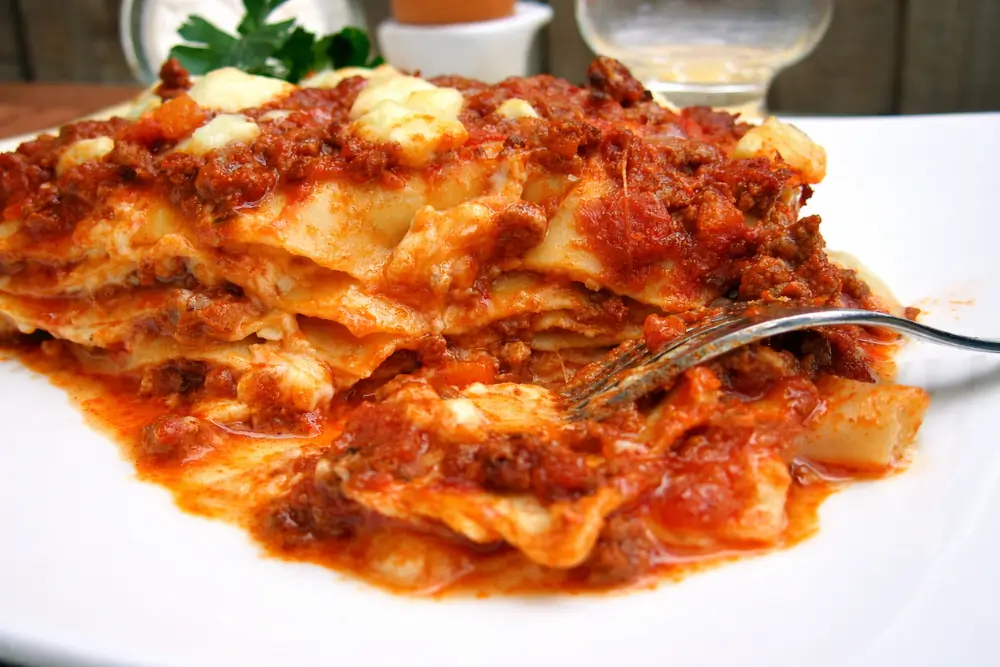 Close-up of a slice of lasagna showing layers of pasta, meat sauce, and melted cheese.