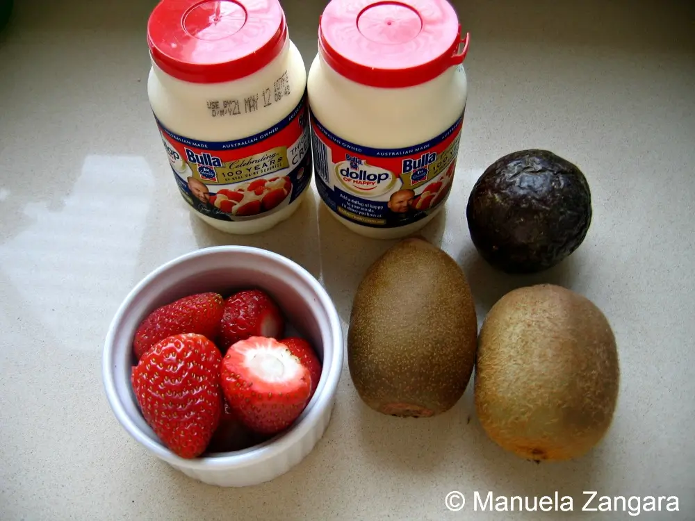 Ingredients prepared for pavlova including fruit and cream.