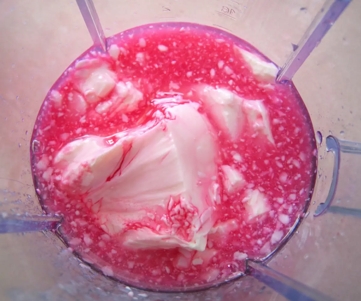 Yoghurt and rose syrup mixture in a blender before being blended until smooth.