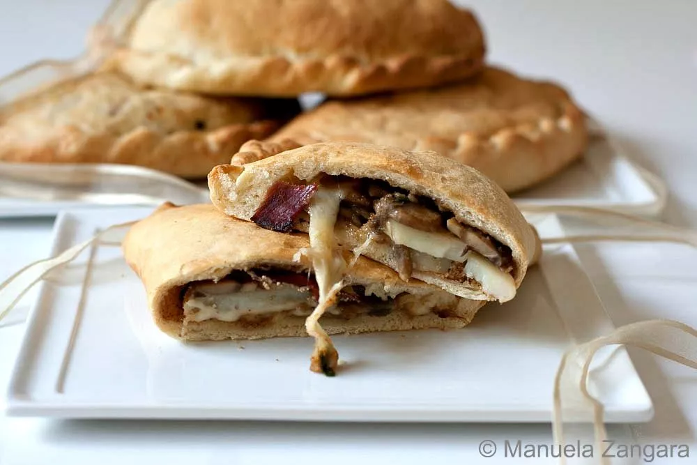 Freshly baked Mushroom and Asiago Calzoni filled with mushrooms, speck, and melted cheese.