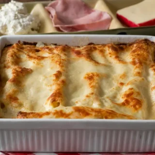 Ham and Cheese Cannelloni baked in a ceramic dish and topped with golden béchamel sauce.