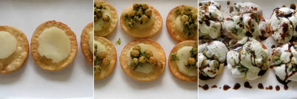 Papri topped with potatoes, chickpeas, yoghurt, and tamarind chutney during assembly.