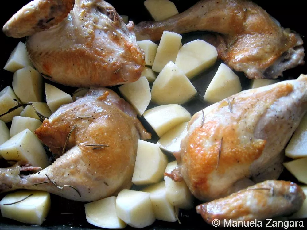Chicken pieces and potatoes roasting together in the oven until golden brown.