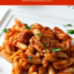 A plate of cavatelli coated in pork ragù and topped with grated cheese and parsley.