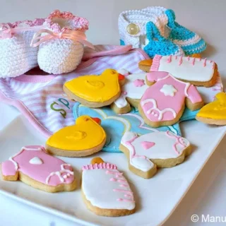 Baby Shower Shortbread Cookies decorated with pink onesies, yellow duck, and white baby bottle cookies.