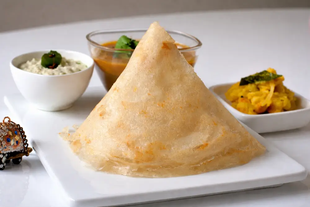 Dosa Golden crispy cone-shaped dosa served with accompaniments.