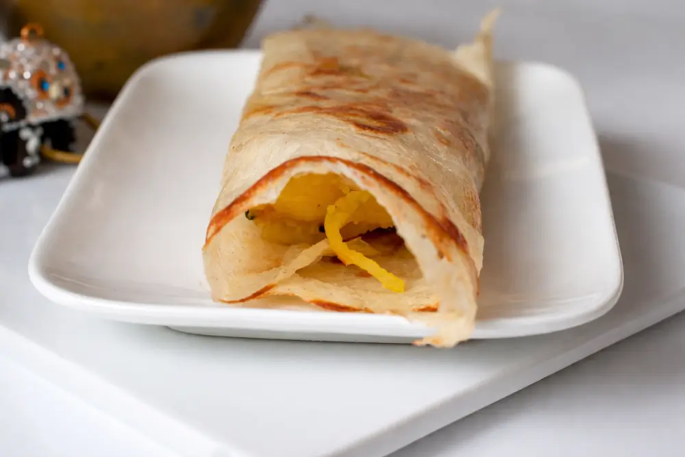 Close-up of a rolled dosa cut open, with soft spiced potato filling inside.