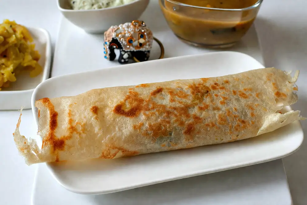 Masala dosa rolled and served on a white plate.
