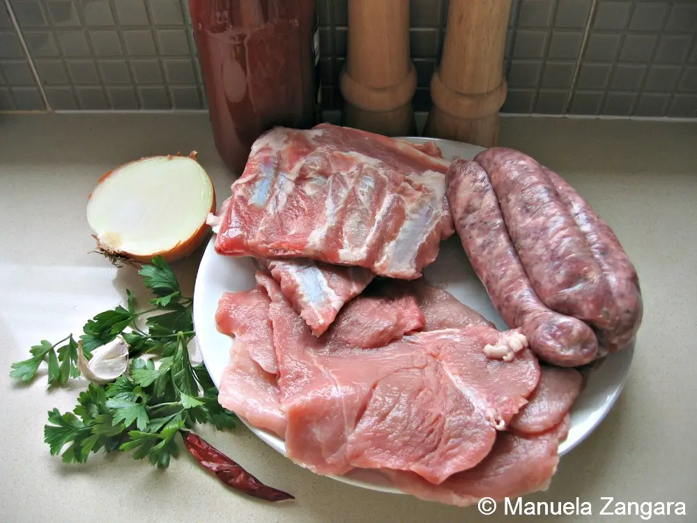 A plate of pork schnitzels, spare ribs, and sausages with onion, garlic, parsley, and chilli prepared for the ragù.