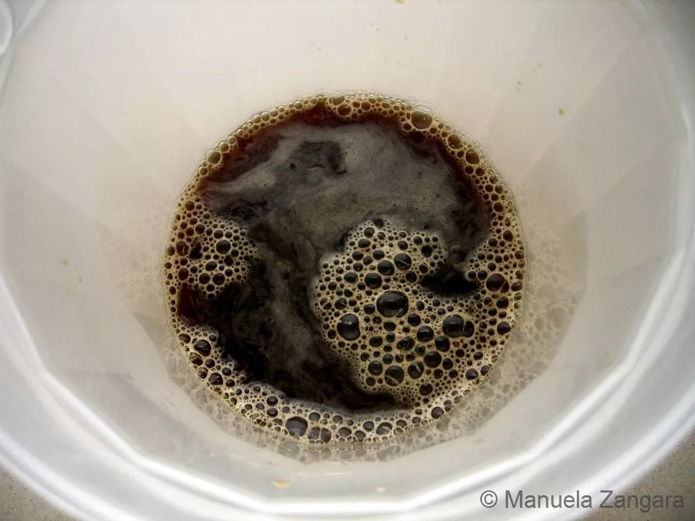 Freshly brewed espresso mixed with water and sugar in a bowl.