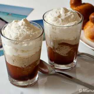 Glasses of Granita al Caffè con Panna served with Sicilian brioche on a white table.