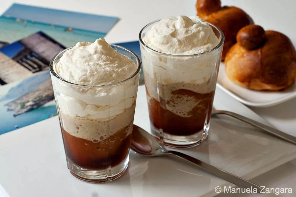 Granita al caffe' con panna Glasses of Granita al Caffè con Panna served with Sicilian brioche on a white table.