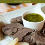 Sliced beef bollito served with carrots, potatoes, and a small bowl of Salsa Verde.