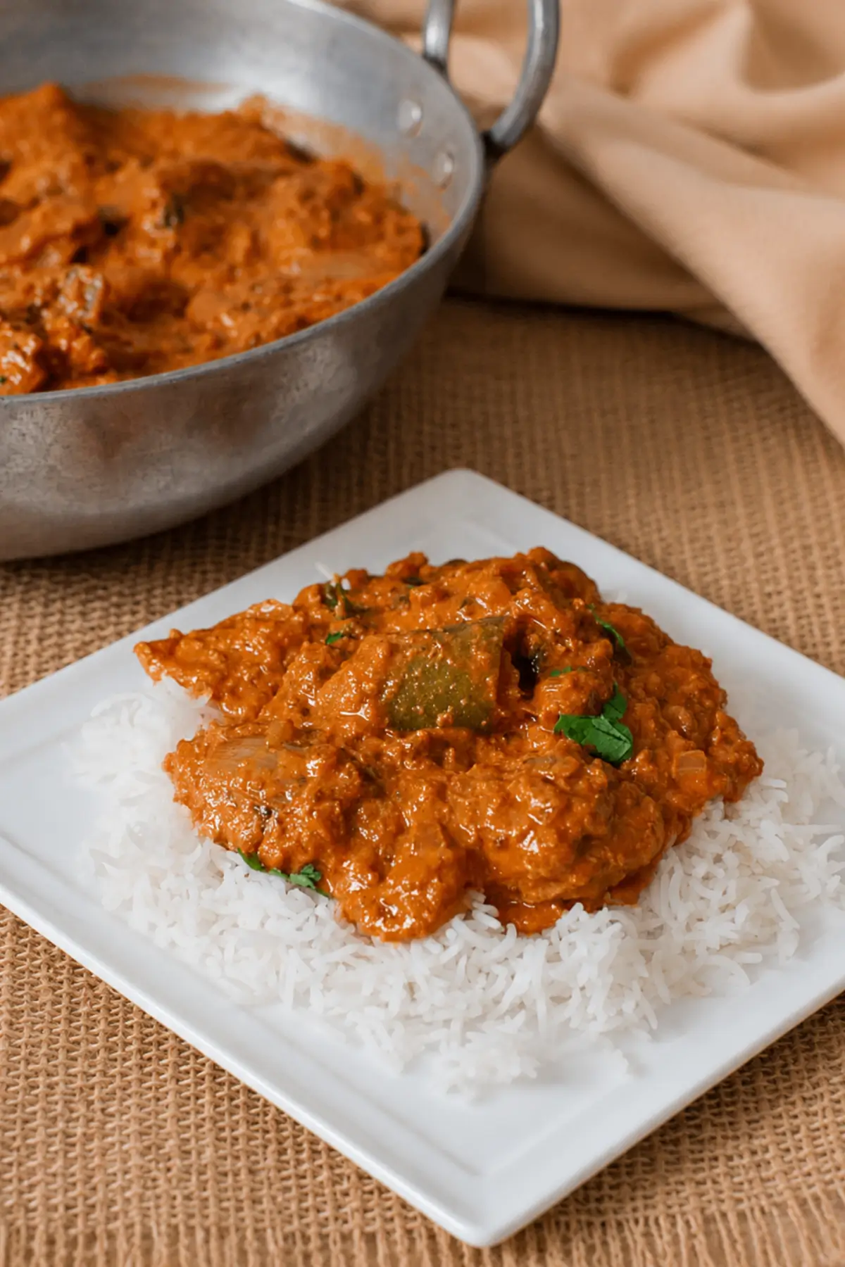 Tikka curry served over fluffy basmati rice on a white plate.