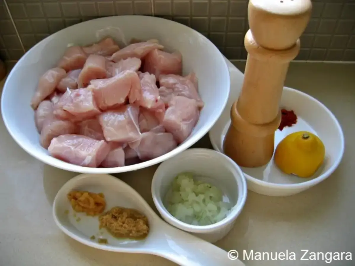 Ingredients for the first marinade arranged in bowls beside cubed chicken.