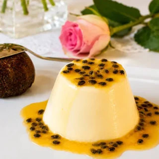 Passion Fruit Panna Cotta with Vanilla Cream served with fresh passion fruit coulis on a white plate.