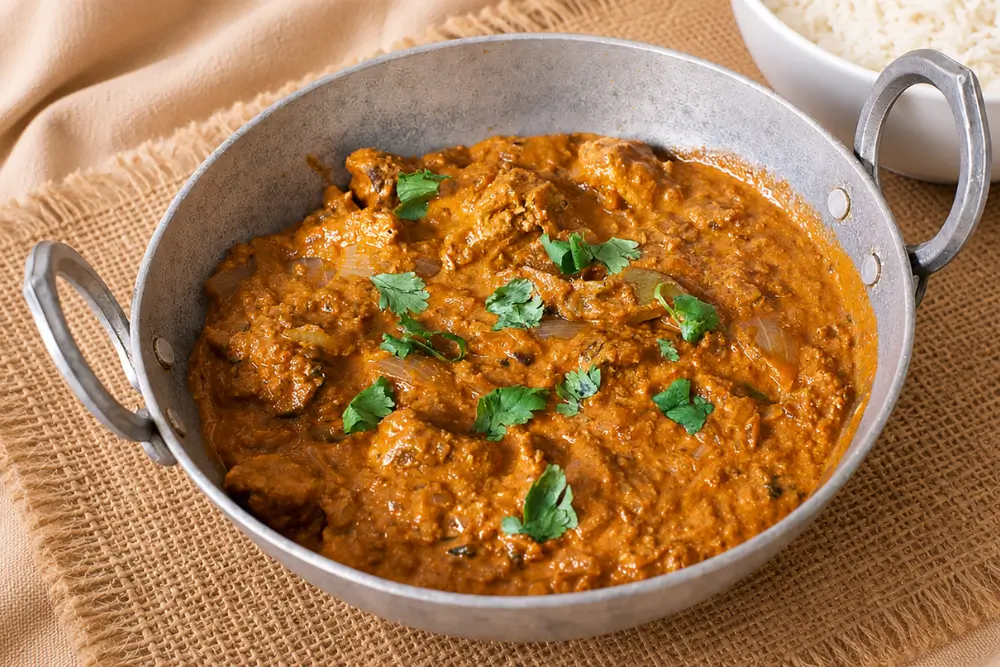 Chicken Tikka Masala served over basmati rice with extra curry in the background.