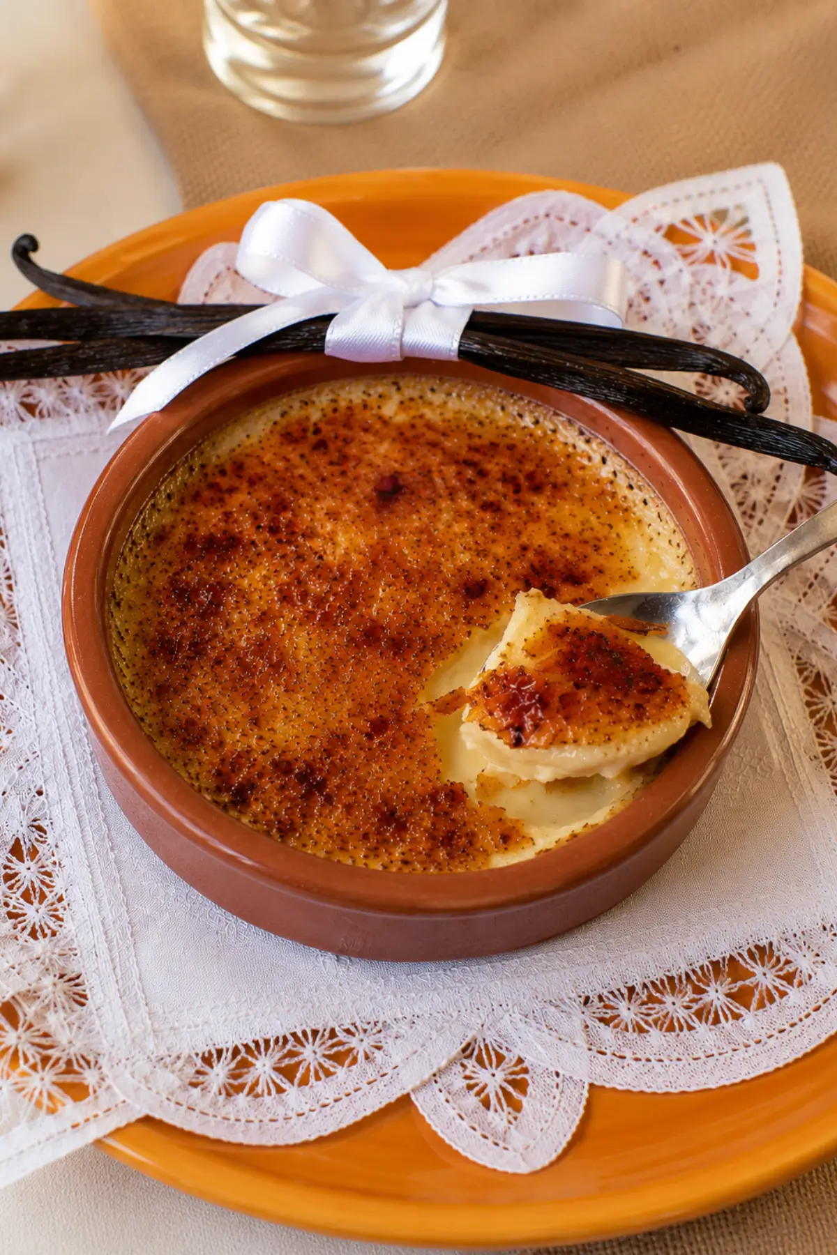 Spoon lifting creamy custard and caramel topping from a freshly brûléed dessert.