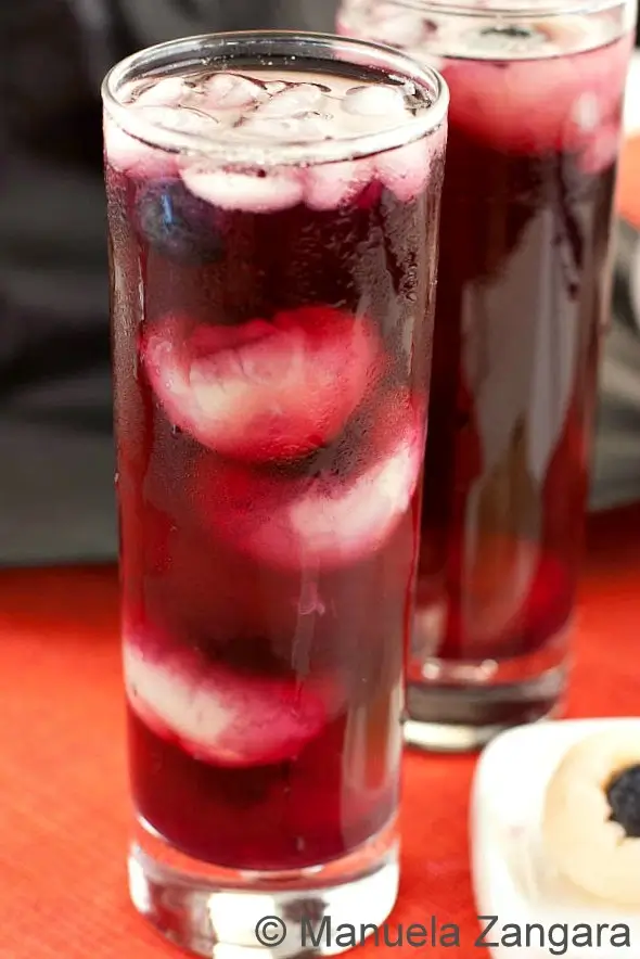 Tall glasses of Halloween Punch recipe filled with ice and floating lychee blueberry “eyeballs.”