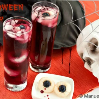 Two glasses of Halloween Punch with lychee eyeballs, skull and spider web decorations.