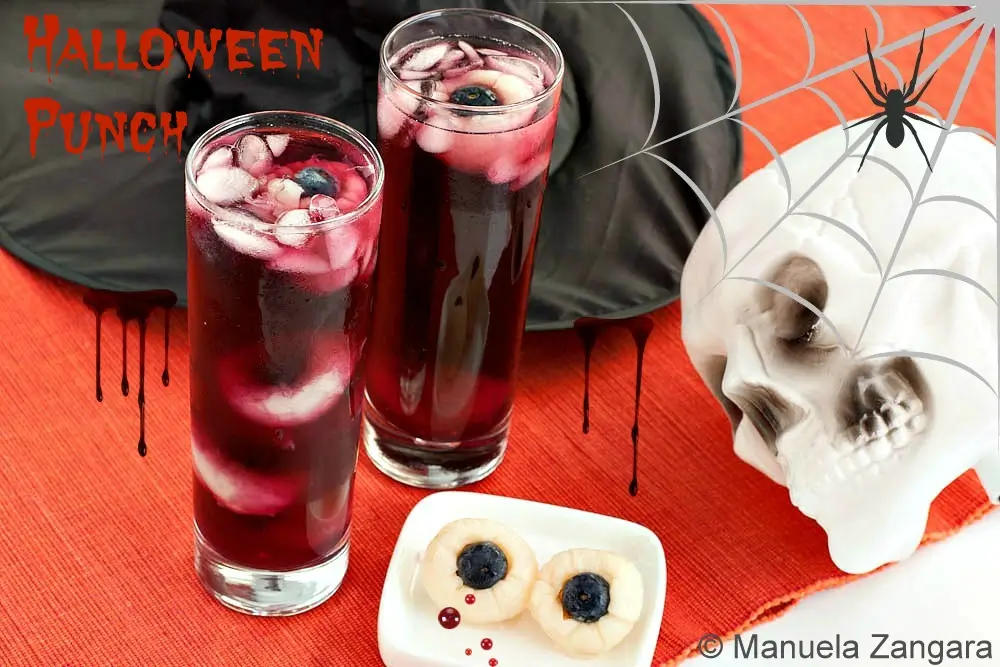 Two glasses of Halloween Punch with lychee eyeballs, skull and spider web decorations.