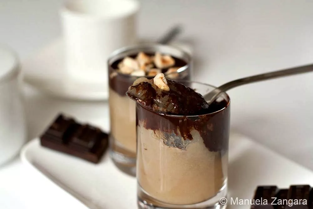 Maple Pear Mousse Shooters with Chocolate and Hazelnuts Two pear mousse shooters topped with dark chocolate and crushed hazelnuts served in small glasses with a spoon.