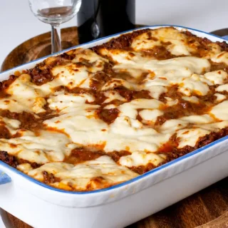 Freshly baked lasagne in a ceramic baking dish with golden melted cheese on top.