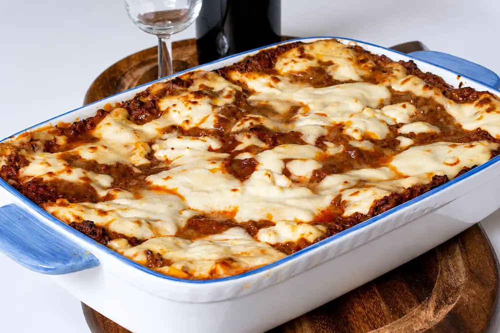 Freshly baked lasagne in a ceramic baking dish with golden melted cheese on top.