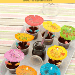 Close-up of Muddy Puddle Cups with colourful paper umbrellas and fizzy worms.