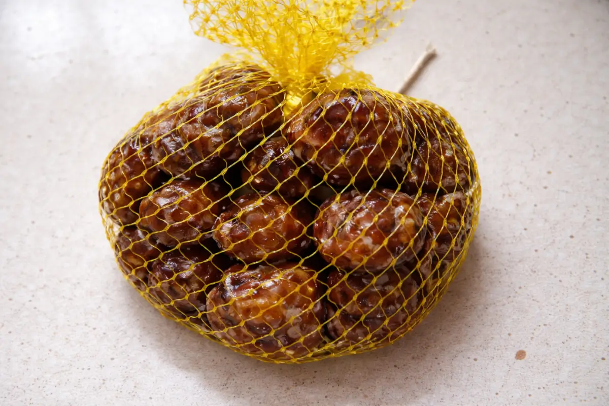 Chestnuts coated in syrup placed in a yellow mesh bag before soaking.