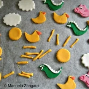 Homemade fondant decorations for the Peppa Pig cake, including ducks, dinosaurs, and flowers.