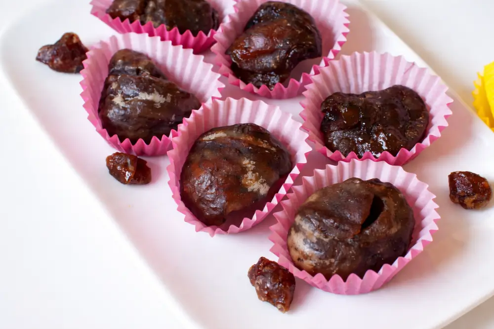 Close-up of marrons glacés in pink paper cups on a plate.