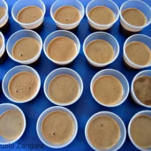 Rows of small cups filled with chocolate panna cotta setting in the fridge.