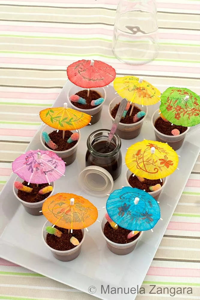 Finished Muddy Puddle Cups with paper umbrellas and fizzy worms on a tray.